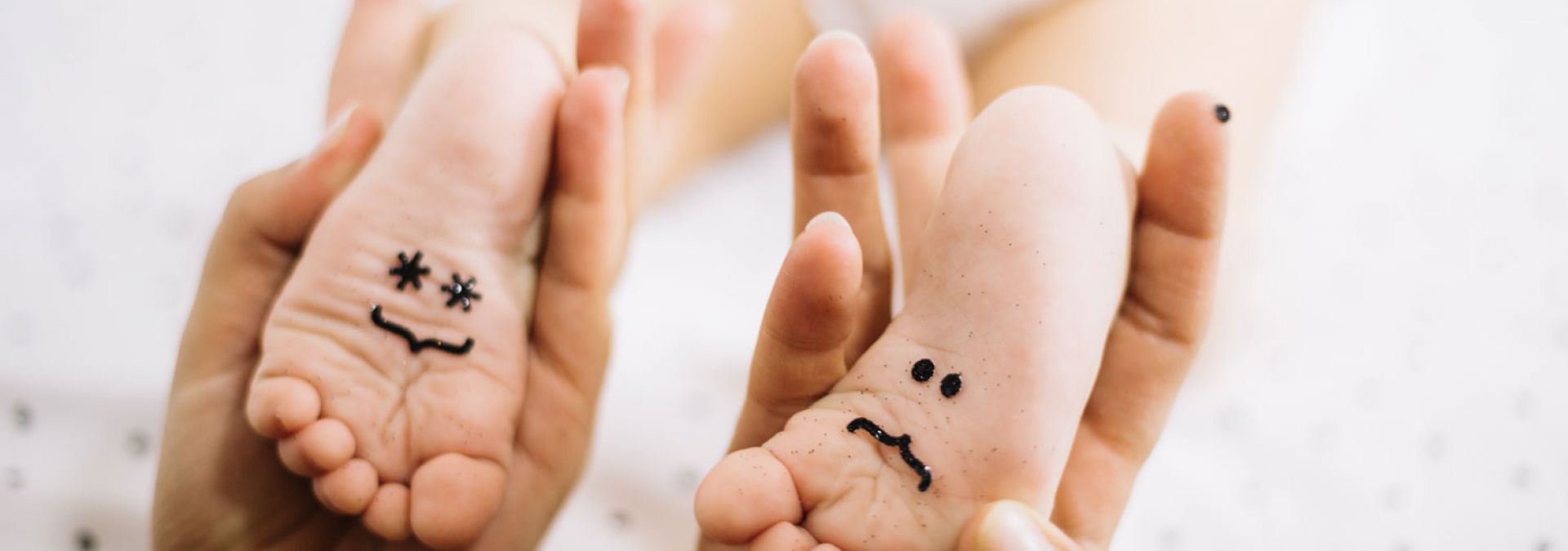 Leevke Mensen Füße eines Babies mit einem lachenden und einem traurigen Smiley